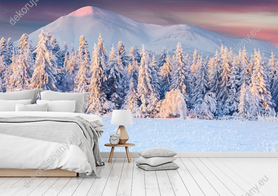 Wizualizacja fototapety przedstawia zimową porę. Góry i las pokryte śniegiem o wschodzie słońca. Fototapeta do salonu, sypialni, pokoju dziennego, gabinetu, biura, przedpokoju.