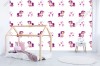 Wizualizacja tapety na ścianę do pokoju dziecięcego w różowe, bajkowe koniki, którym towarzyszą gwiazdy, na białym tle.