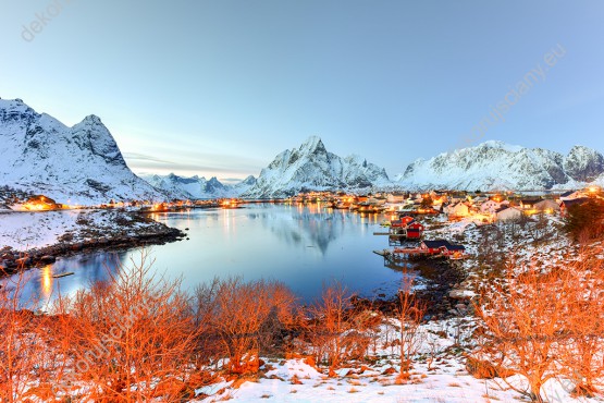 Wzornik fototapety z zimową aurą przedstawiająca ośnieżone góry, jezioro i czerwone krzewy zdobiące norweski krajobraz. Fototapeta do pokoju dziennego, sypialni, salonu, biura, gabinetu, przedpokoju i jadalni.