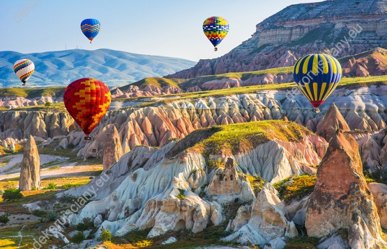 Wzornik fototapety z widokiem na kolorowe balony lecące nad kanionami i górskimi szczytami w Turcji. Fototapeta do pokoju dziennego, sypialni, salonu, biura, gabinetu, przedpokoju i jadalni.
