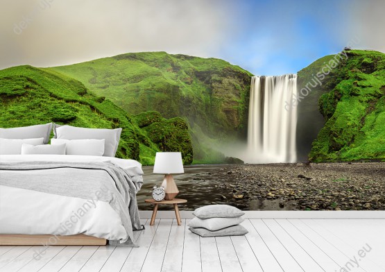 Wizualizacja fototapety z widokiem na wodospad wypływający z zielonych gór na Islandii. Fototapeta do pokoju dziennego, sypialni, salonu, biura, gabinetu, przedpokoju i jadalni.