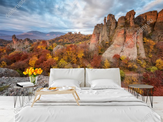 Wizualizacja fototapety przedstawiająca piękny krajobraz z widokiem na skaliste góry w kolorowe drzewa w jesiennych barwach. Fototapeta do pokoju dziennego, sypialni, salonu, biura, gabinetu, przedpokoju i jadalni.