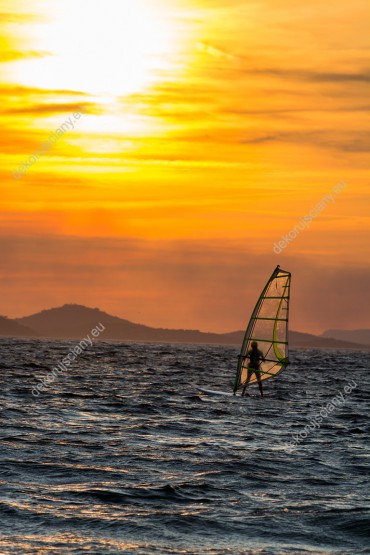 Wzornik fototapety z widokiem na windsurfingowca na wzburzonej wodzie, o zachodzie słońca. Fototapeta do pokoju dziennego, salonu, biura, gabinetu, sypialni, przedpokoju i jadalni.