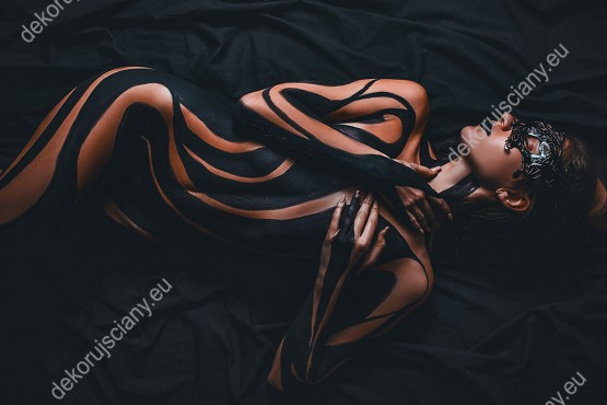 Wzornik, piękna kobieta z ozdobionym ciałem i czarną maską na twarzy w pozycji leżącej.