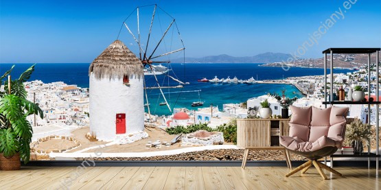 Wizualizacja fototapety z widokiem na tradycyjny wiatrak górujący nad białymi domami greckiego miasta, na wyspie Mykonos. Fototapeta do pokoju dziennego, sypialni, salonu, biura, gabinetu, przedpokoju i jadalni.