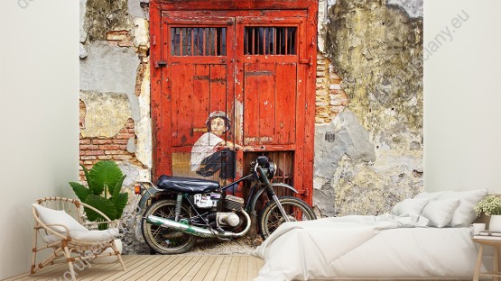Wizualizacja fototapety  z kategorii murali przedstawia motocyklistę siedzącego na motorze, na tle starych, czerwonych drzwi. Fototapeta do pokoju dziennego, młodzieżowego, sypialni, salonu, biura, gabinetu, przedpokoju i jadalni.