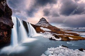 Wzornik fototapety z widokiem na zimowe, górskie wodospady o zachodzi słońca w Islandii. Fototapeta do pokoju dziennego, sypialni, salonu, biura, gabinetu, przedpokoju i jadalni.
