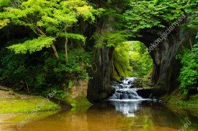Wzornik fototapety z widokiem na wodospad płynący pod skalnym łukiem, wśród bujnej zieleni lasu, w Japonii. Fototapeta do pokoju dziennego, sypialni, salonu, biura, gabinetu, przedpokoju i jadalni.