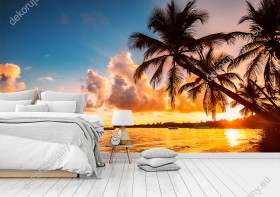 Wizualizacja fototapety z widokiem tropikalnej plaży i egzotycznych palm przy wodzie ozłoconej promieniami zachodzącego słońca na Dominikanie. Fototapeta do pokoju dziennego, sypialni, salonu, biura, gabinetu, przedpokoju i jadalni.