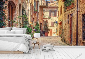 Wizualizacja fototapety przedstawiająca spokojną uliczkę ozdobioną kwiatami, w rejonie Toskanii we Włoszech. Fototapeta do pokoju dziennego, młodzieżowego, sypialni, salonu, biura, gabinetu, przedpokoju i jadalni.