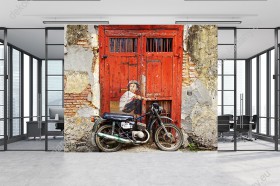 Wizualizacja fototapety  z kategorii murali przedstawia motocyklistę siedzącego na motorze, na tle starych, czerwonych drzwi. Fototapeta do pokoju dziennego, młodzieżowego, sypialni, salonu, biura, gabinetu, przedpokoju i jadalni.